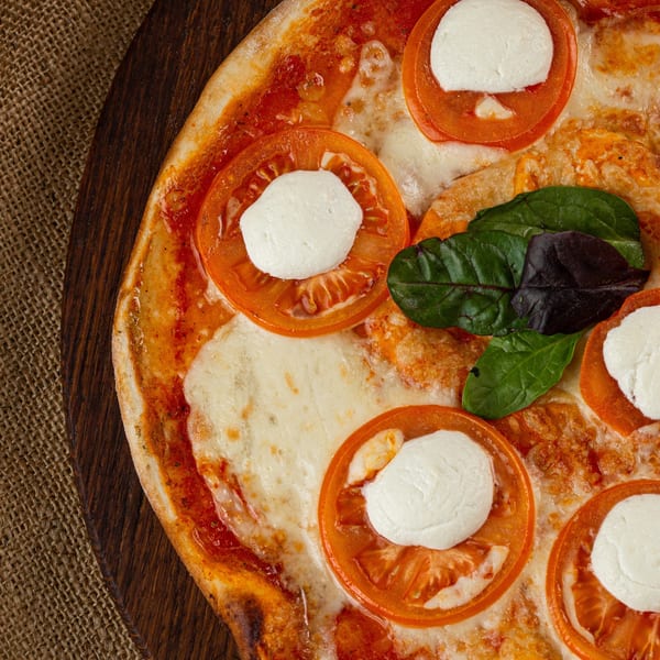 Close-up of a Bella Donna Pizzeria pizza with fresh mozzarella, tomato slices, and basil.